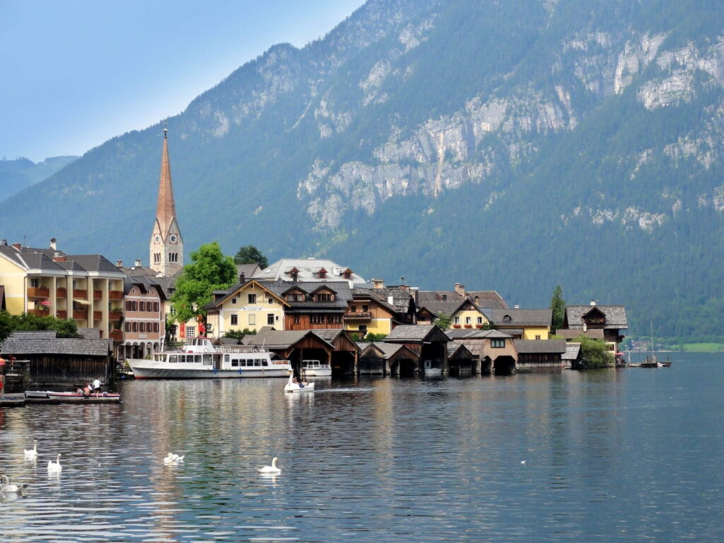 Hallstatt waterfront with church tower and boats on Lake Hallstatt, Austria