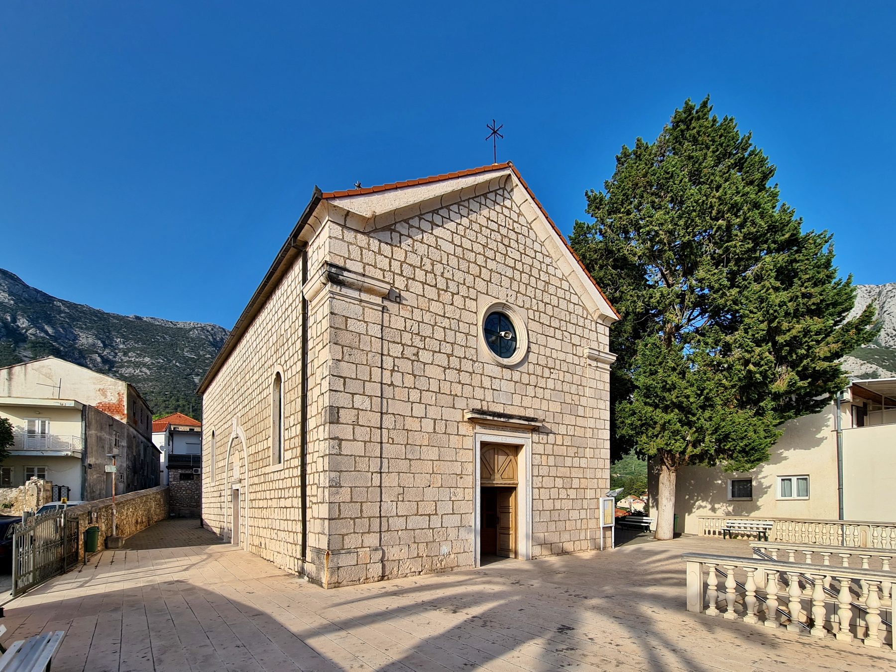 Stone church with red tiled roof and cross in Gradac, Split-Dalmatia County, Croatia