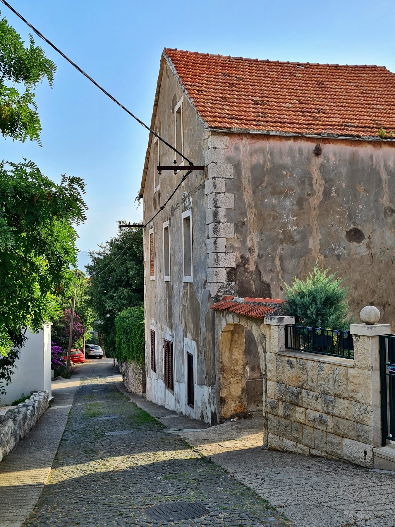 Traditional stone house with red tile roof on a narrow cobblestone street in Gradac, Split-Dalmatia County, Croatia