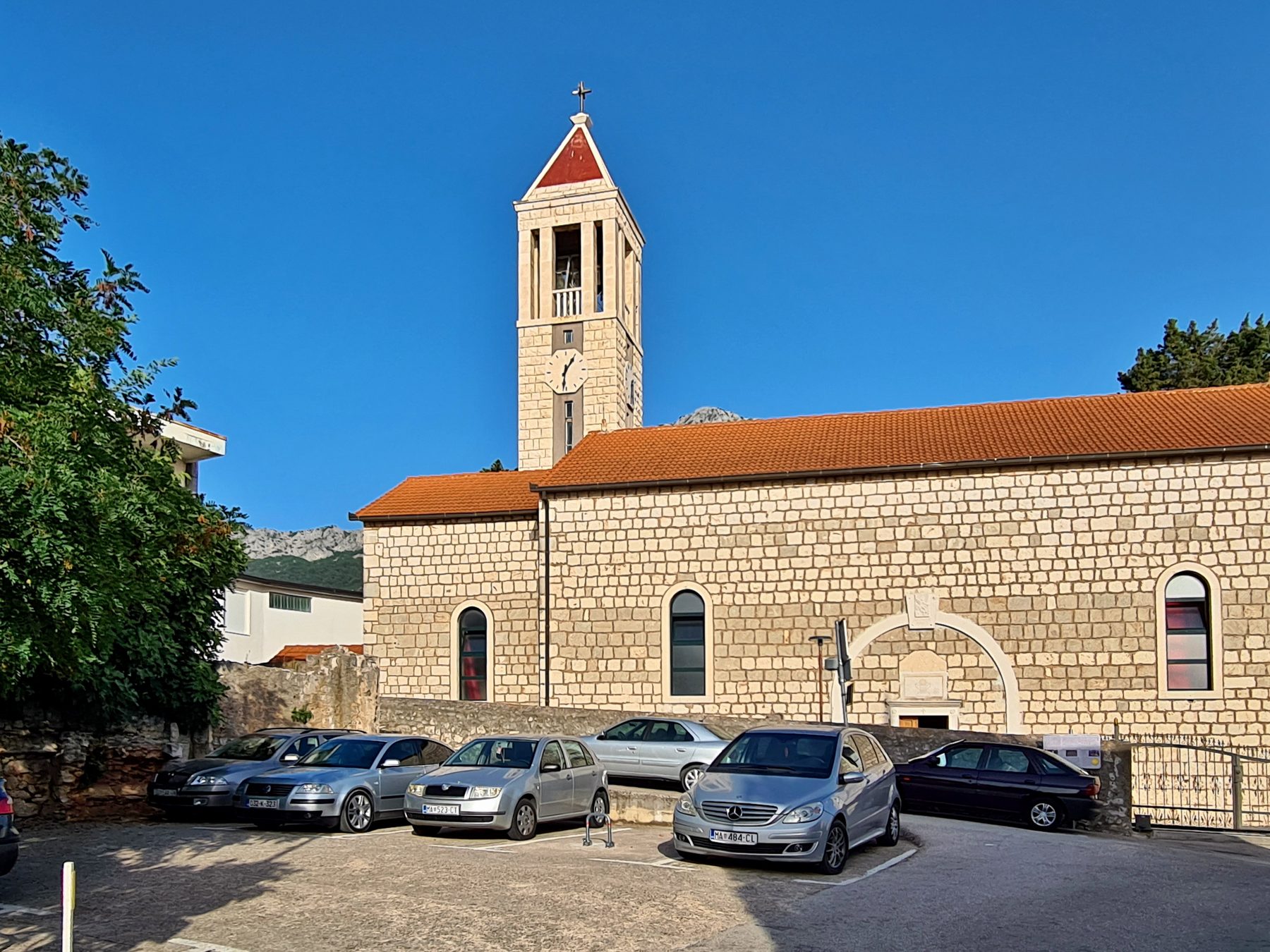 Stone church with clock tower and cross in Općina Gradac, Split-Dalmatia County, Croatia