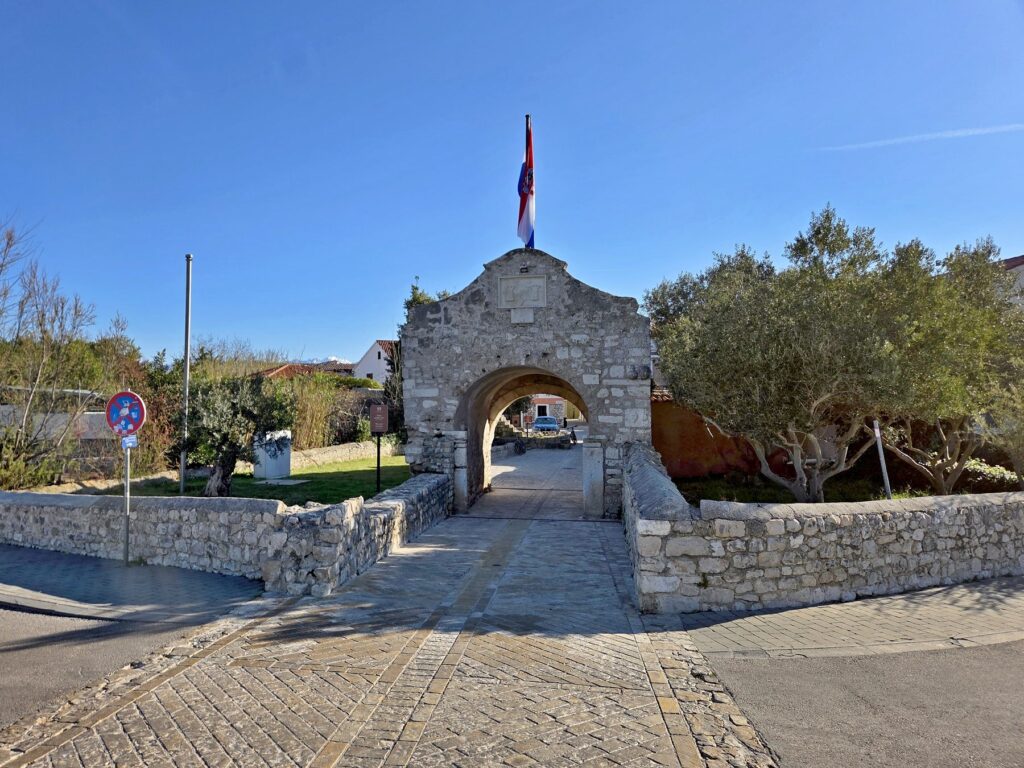 Stone entrance gate with Croatian flag in Nin town, Zadar County, Croatia