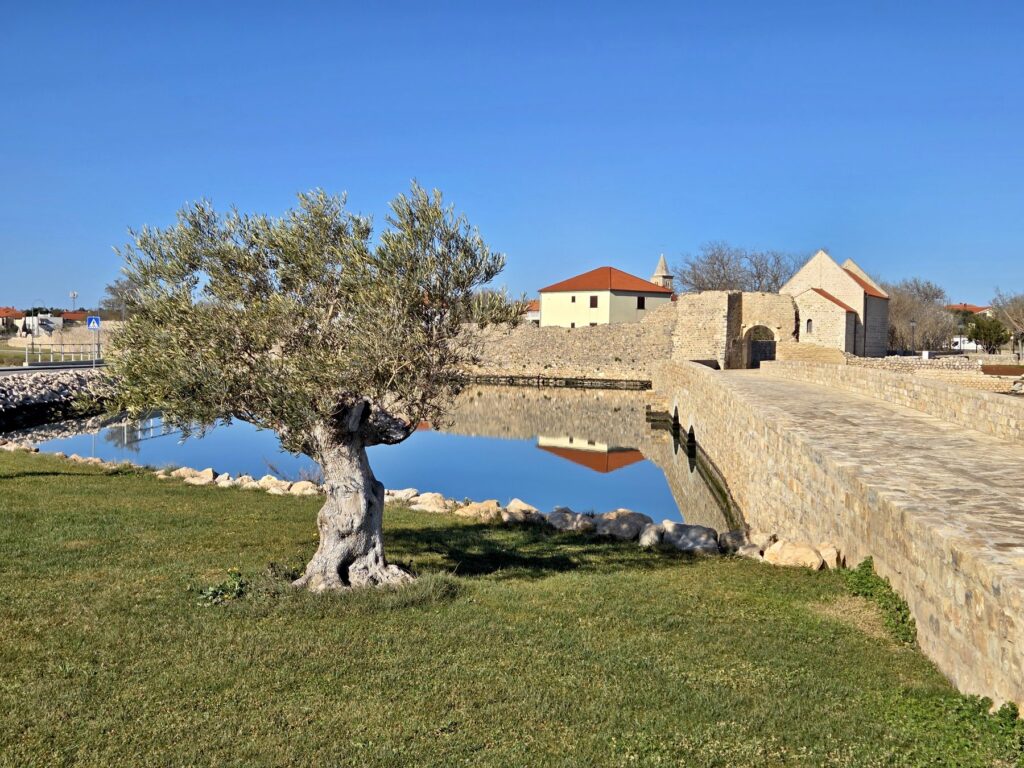 Ancient stone fortress and arched stone bridge with calm water reflections in Nin, Croatia