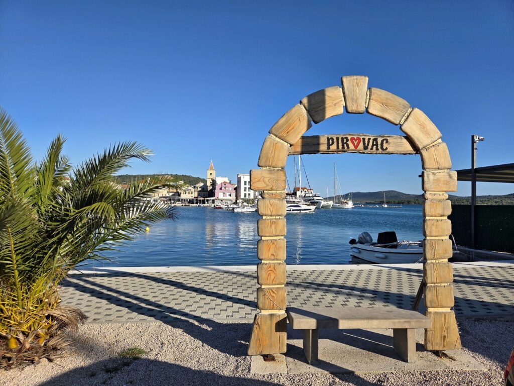 Wooden arch with Pirovac sign overlooking marina and waterfront in Croatia