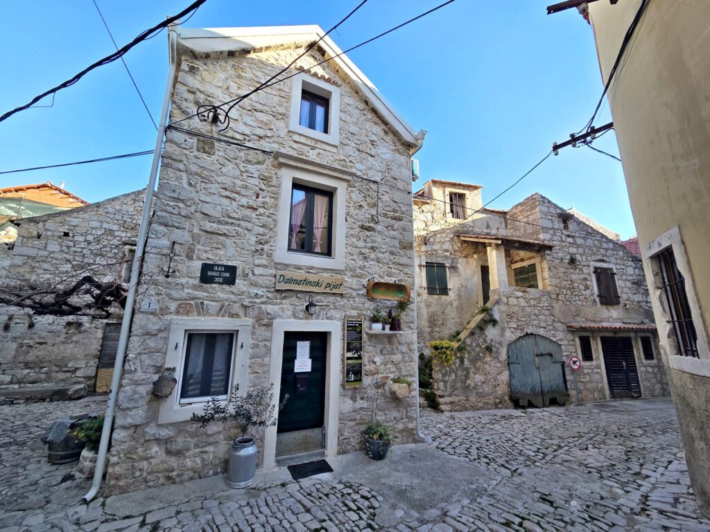 Traditional stone houses with cobblestone streets in Pirovac, Croatia under clear blue sky