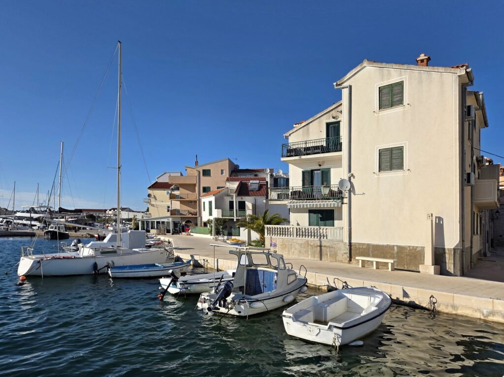 Small boats moored along Pirovac waterfront in Šibenik-Knin County, Croatia under clear blue sky