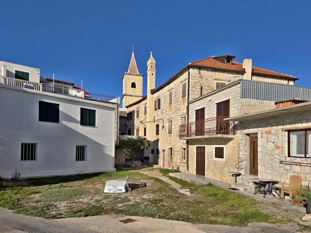 Stone and white buildings with church towers under clear blue sky in Pirovac Croatia