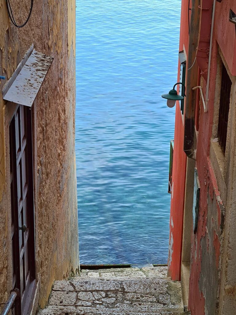 Narrow stone alley leading to the sea in Rovinj old town, Croatia