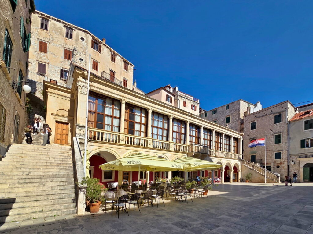 Historic square with stone buildings and café terraces in Šibenik, Croatia