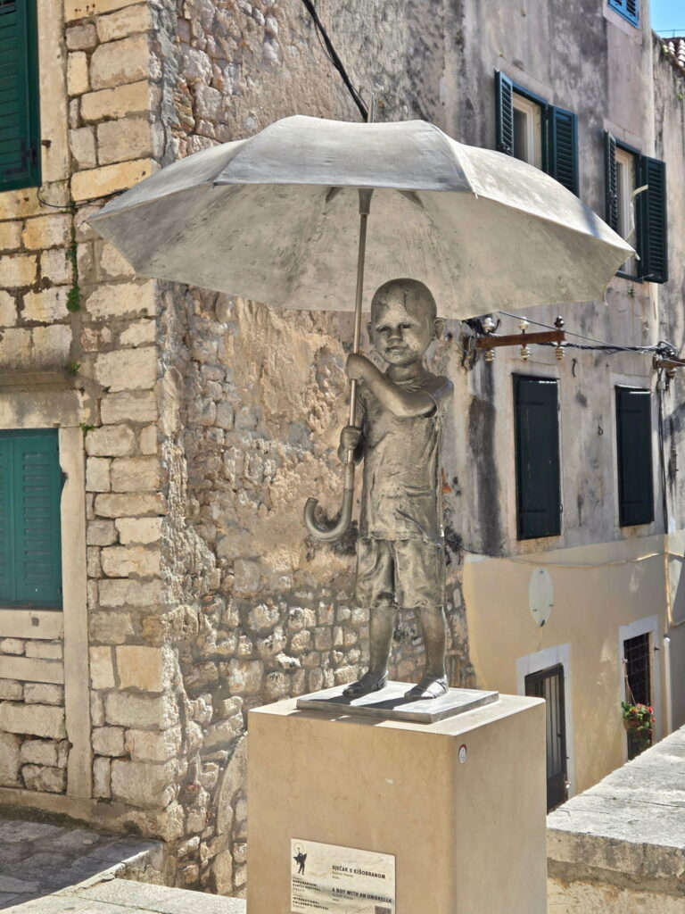 Statue of a boy with umbrella in Šibenik, Croatia