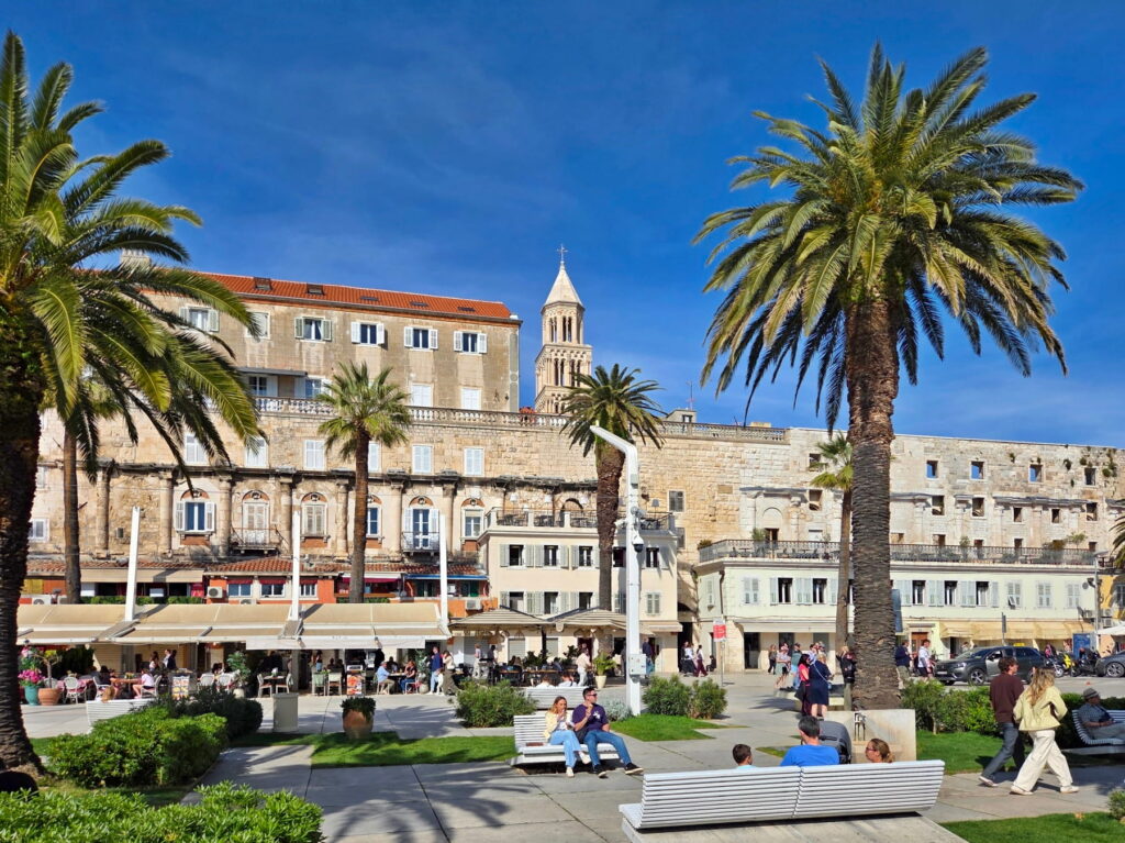 Palm trees and historic stone buildings along the Riva promenade in Split, Croatia.