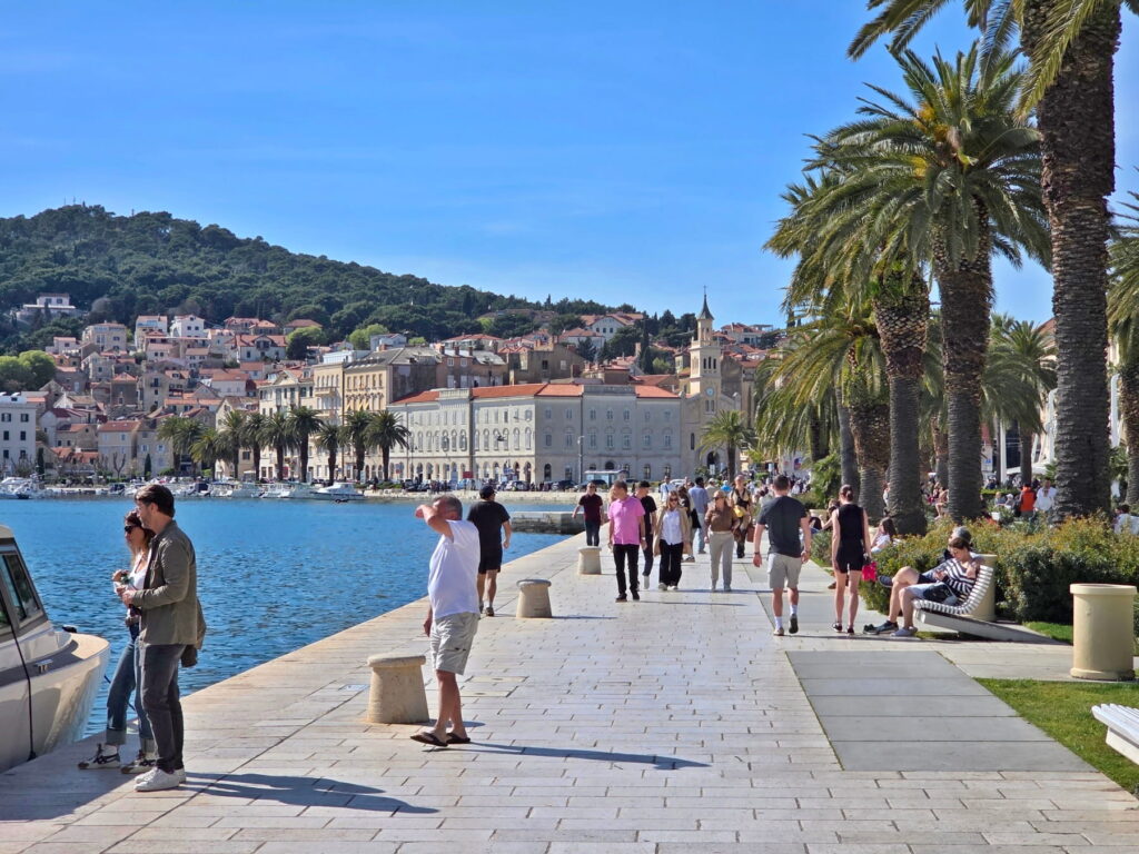 People walking along the palm-lined Riva promenade in Split, Croatia.
