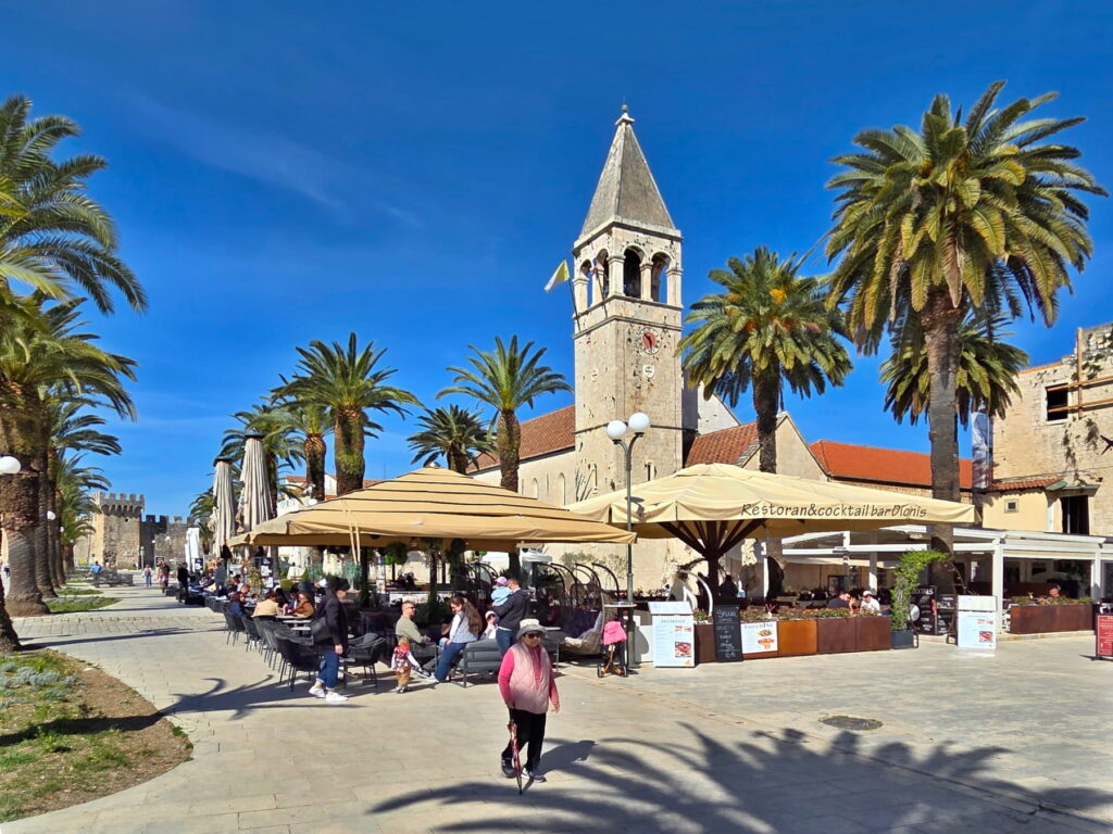Palm-lined promenade and church tower in Trogir, Croatia