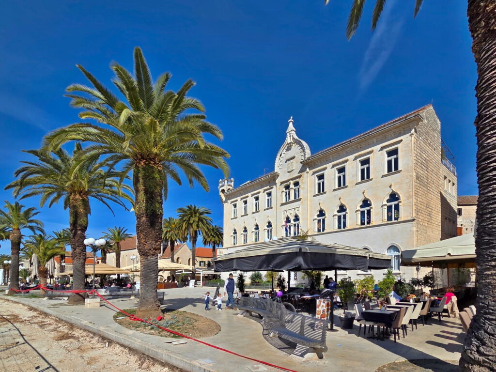Palm-lined square with historic palace in Trogir, Croatia