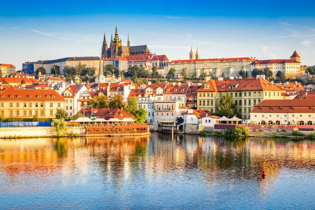 Prague Castle and historic rooftops reflected in the Vltava River, Czech Republic