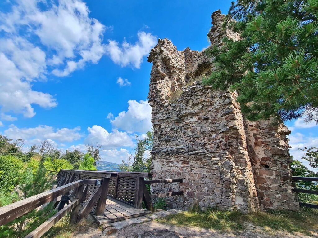 Ruined stone walls of Zubštejn Castle beside a wooden walkway