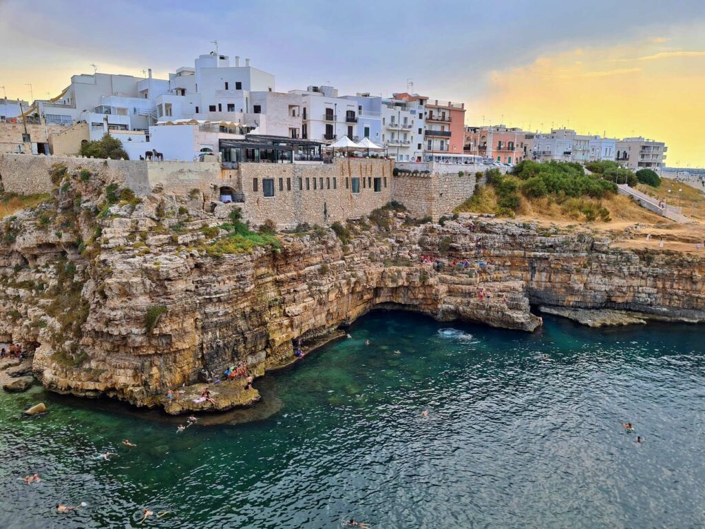 Rocky Adriatic coastline with swimmers in Polignano a Mare, Italy