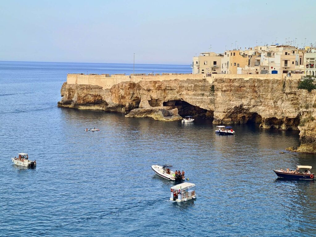 Boats near sea caves along the coast of Polignano a Mare, Italy