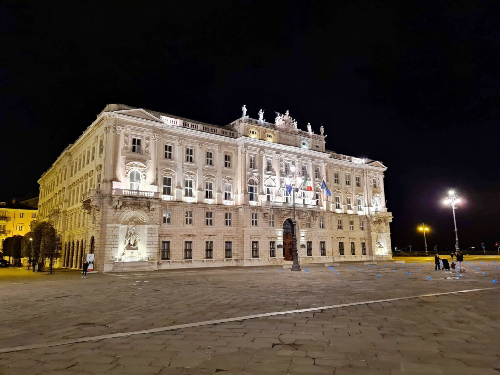 Illuminated historic palace at night in Trieste, Italy