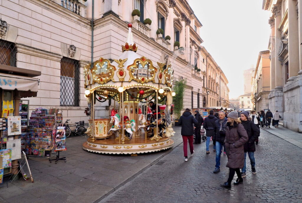 Carousel and pedestrians along a historic street in Vicenza, Italy