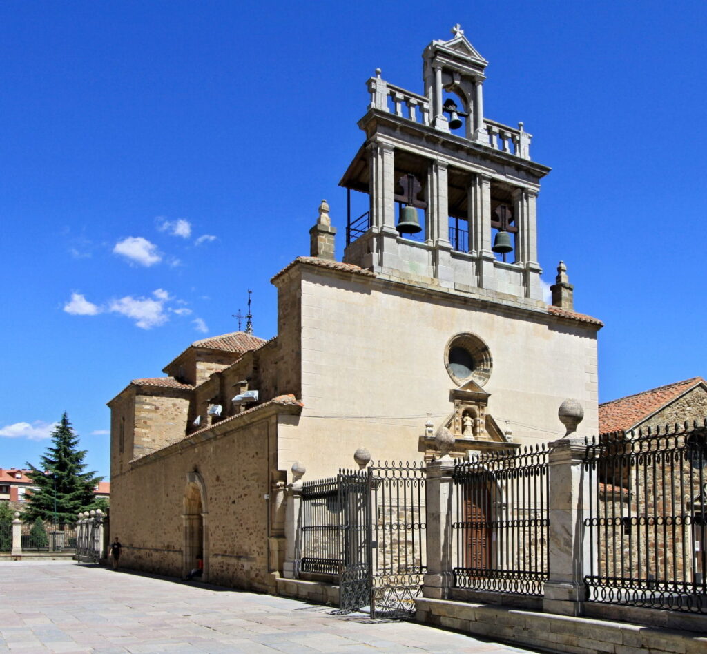 Historic church with bell tower in Astorga, Spain under blue summer sky.