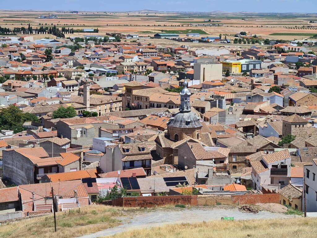 Rooftops and historic church buildings in Consuegra, Spain viewed from above.