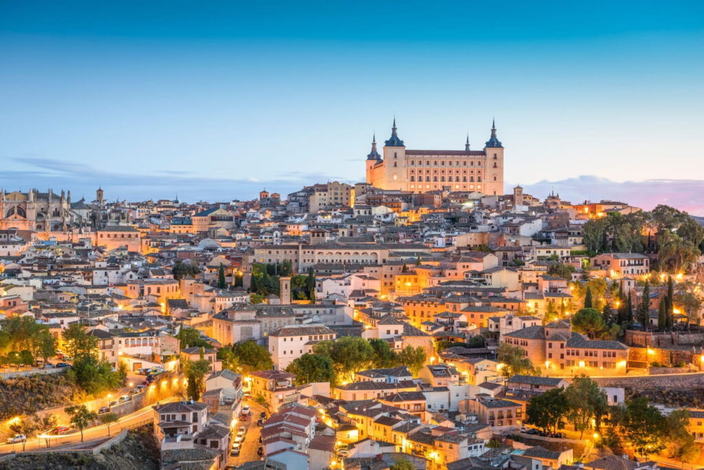 Toledo skyline with Alcázar fortress illuminated at dusk in Spain